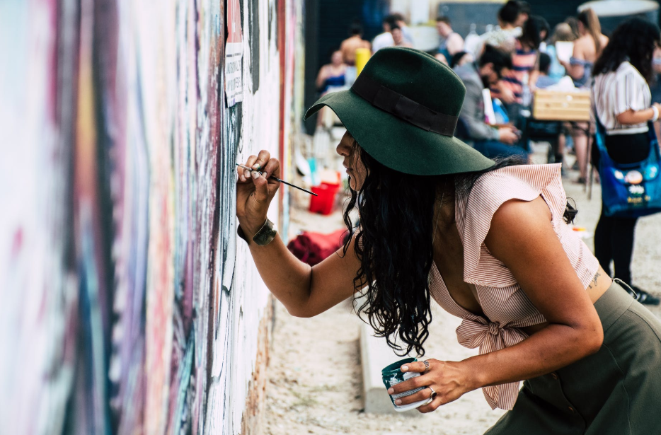 woman wearing hat painting on the wall